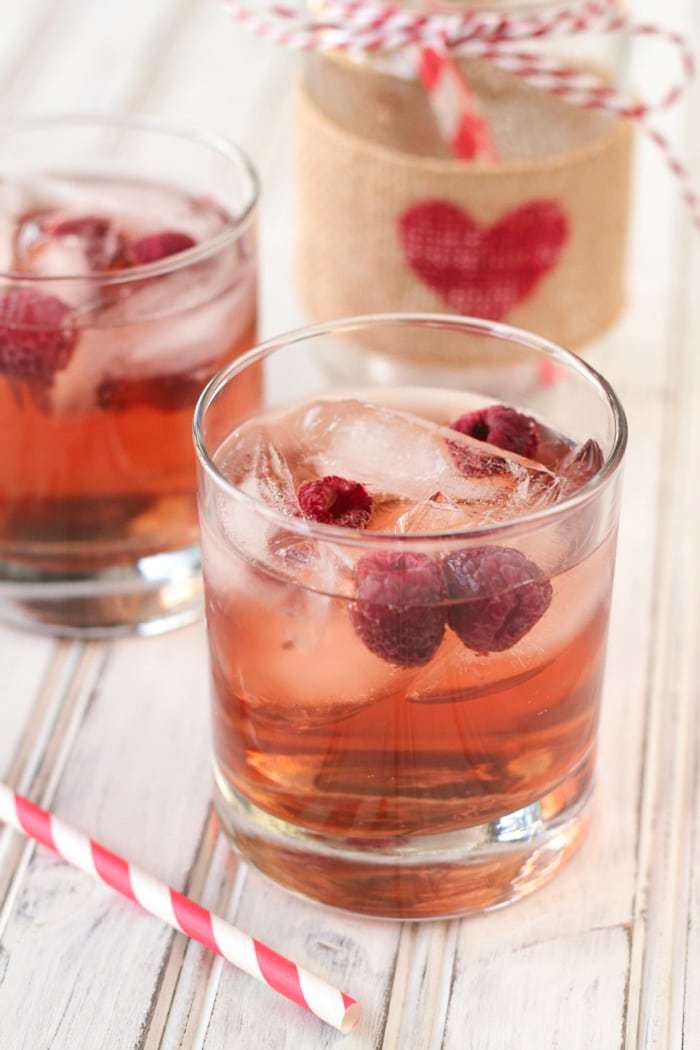 Two cranberry wine spritzers sitting with a red and white striped straw.