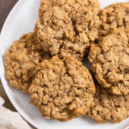 Oatmeal walnut cookies stacked up on a white plate.