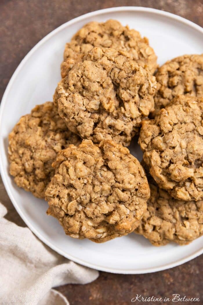 Oatmeal walnut cookies stacked up on a white plate.