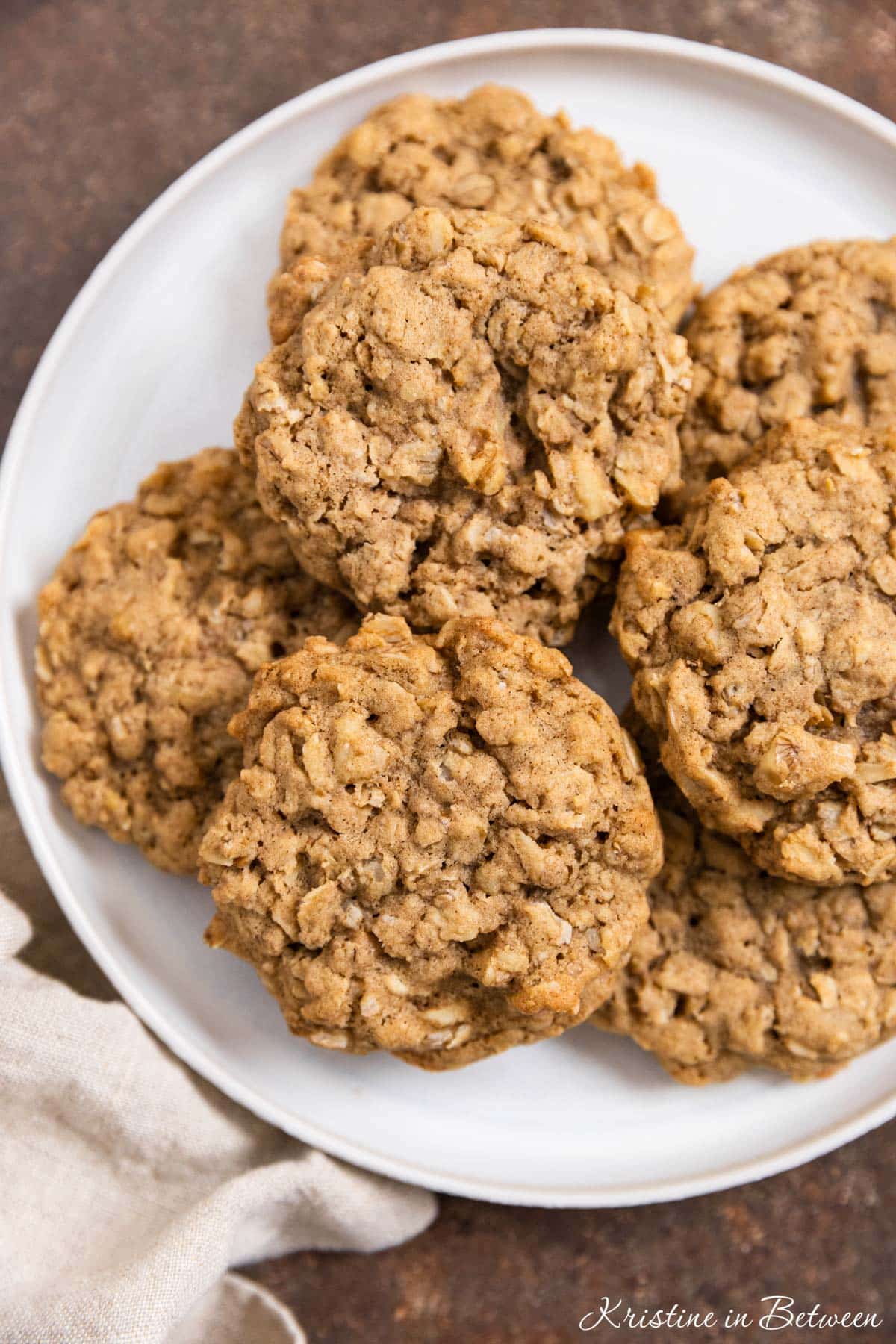 Oatmeal walnut cookies stacked up on a white plate.