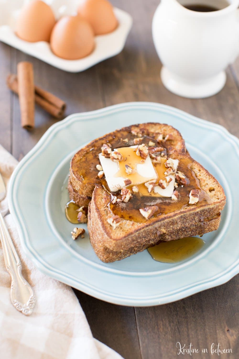 French toast stilton on a plate with a fork and cinnamon sticks in the background.