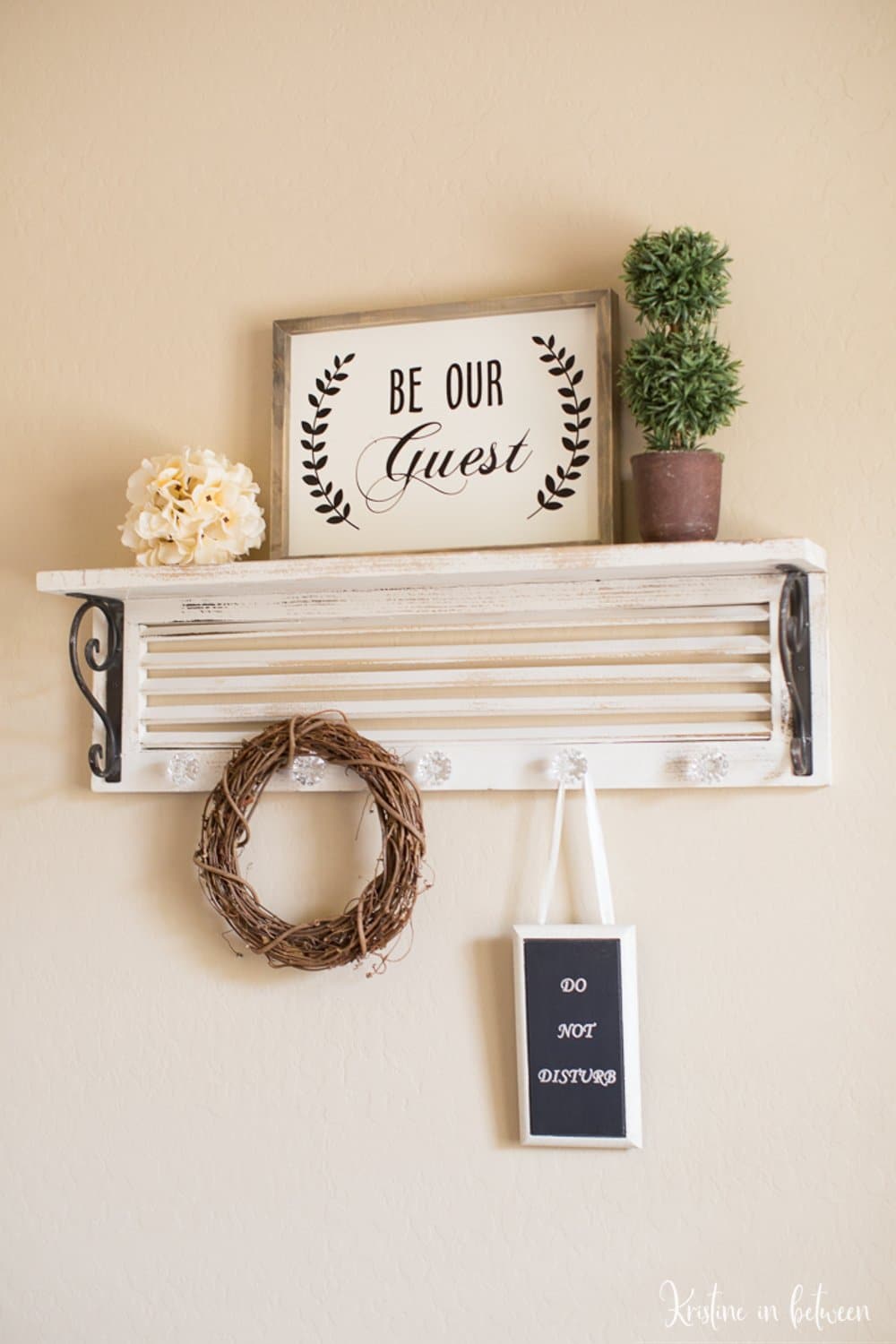 A sign sitting on a wooden shelf that says "Be our guest".