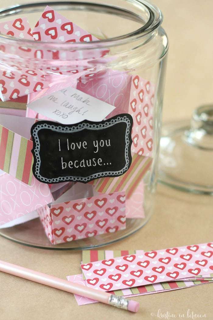 A glass jar filled with love notes sitting with paper and a Valentine pencil.