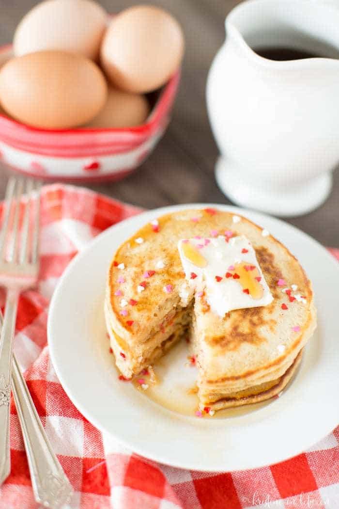 Valentine's Day pancakes sitting on a plate with butter and syrup.