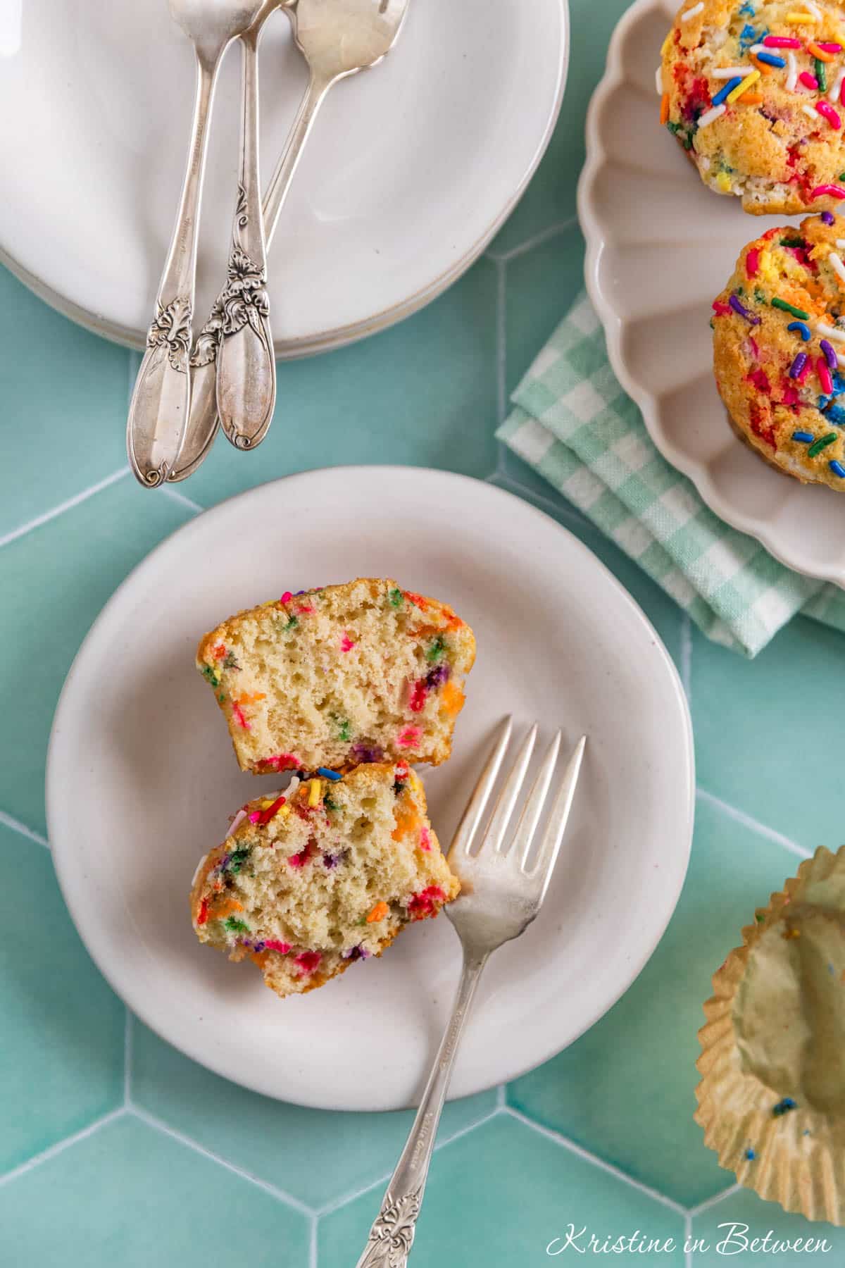 A birthday cake muffin cut in half with a fork sitting next to it.