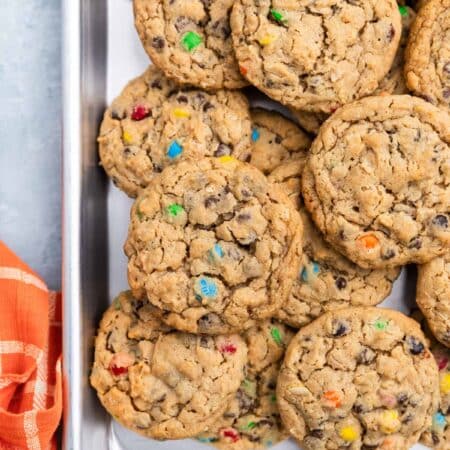 A whole tray of monster cookies sitting with an orange napkin.