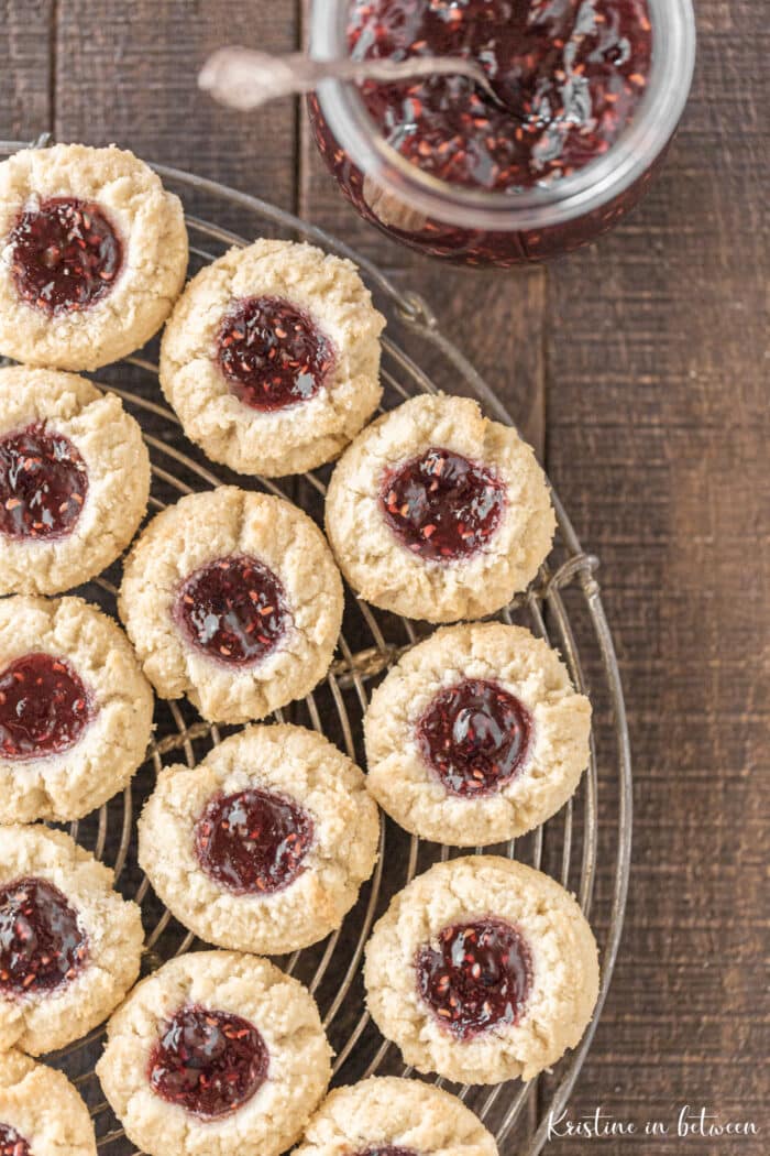 Cookies sitting on a round wire rack with a jar of jam next to them.