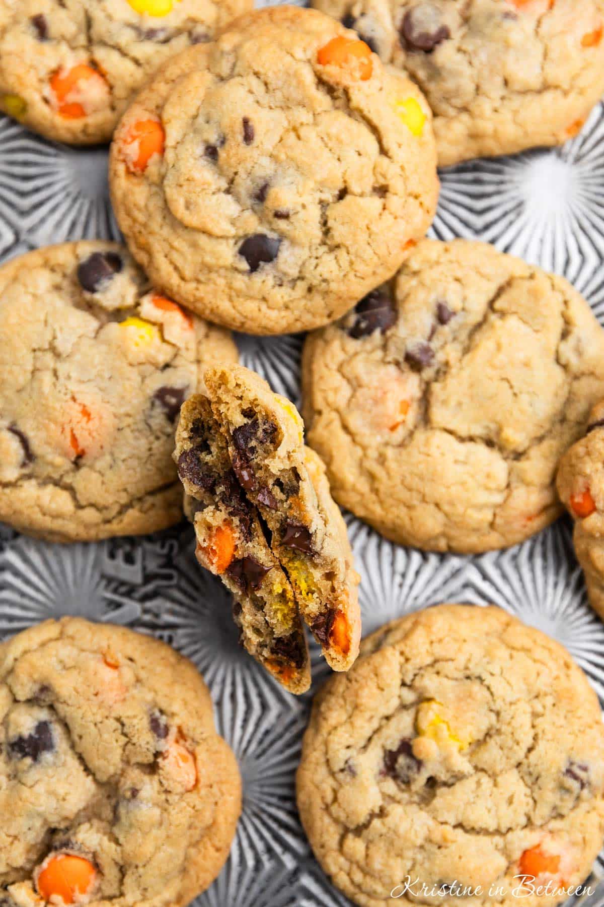 Reese's Pieces cookies laying on an antique baking sheet with a small glass of milk.