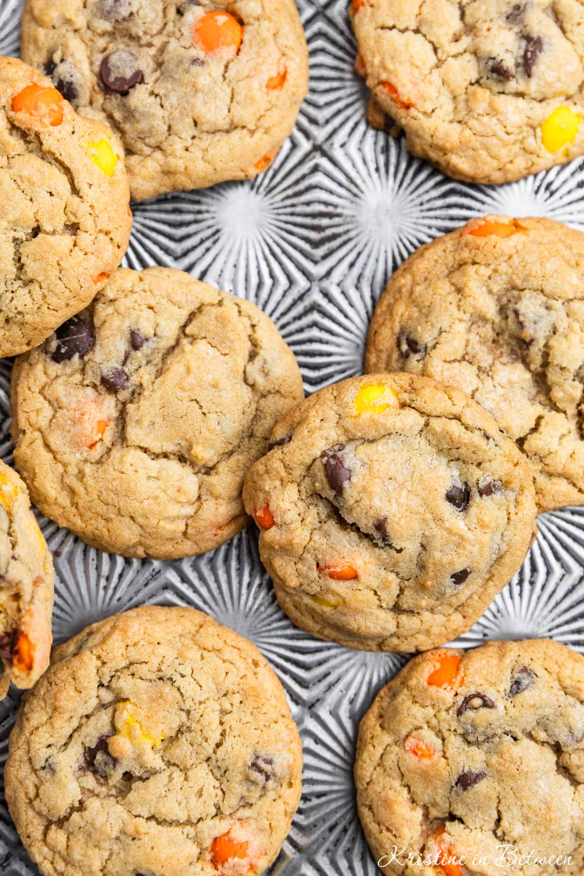 Reese's Pieces cookies laying on an antique baking sheet with a small glass of milk.