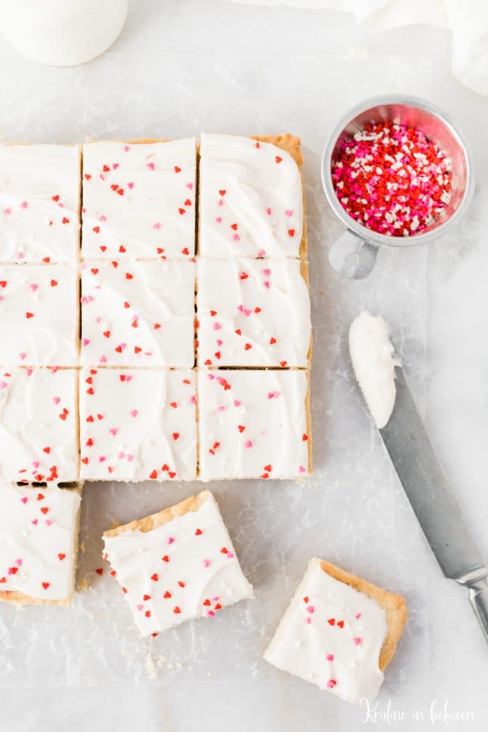 Sugar cookie bars cut up with a knife laying next to them.