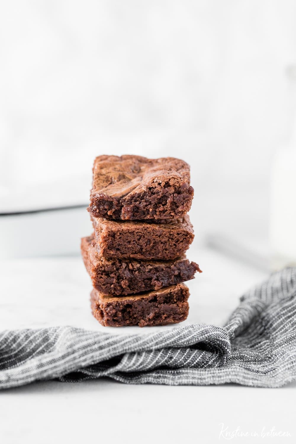 A stack of brownies sitting on a marble plate with a striped napkin.