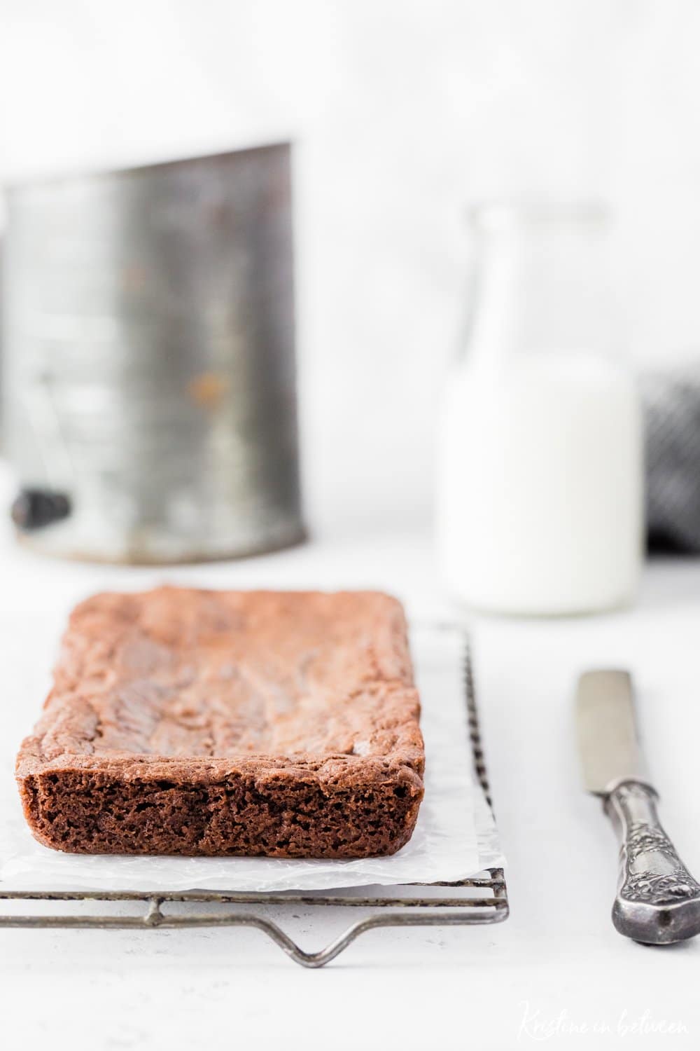 Brownies sitting on a marble tray with a jar of milk in the background.