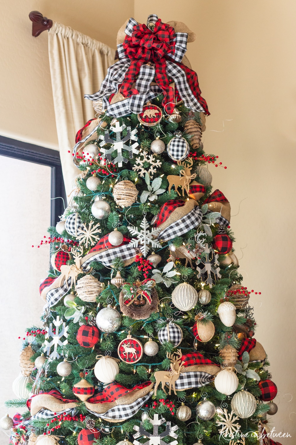 A decorated Christmas tree in red buffalo check, black and white buffalo check, and rustic snowflakes and cabin animals.