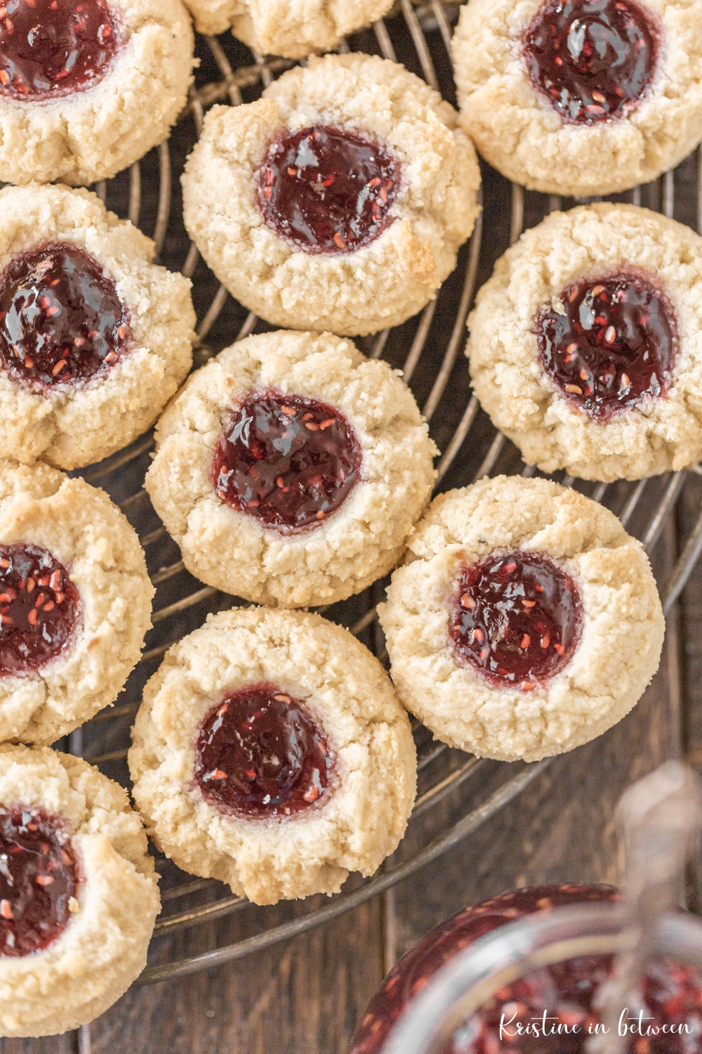 Cookies sitting on a round wire rack with a small jar of jam.