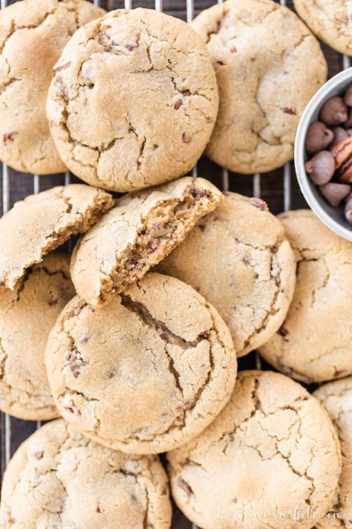 A bunch of cookies on a wooden board one broken in half showing the inside