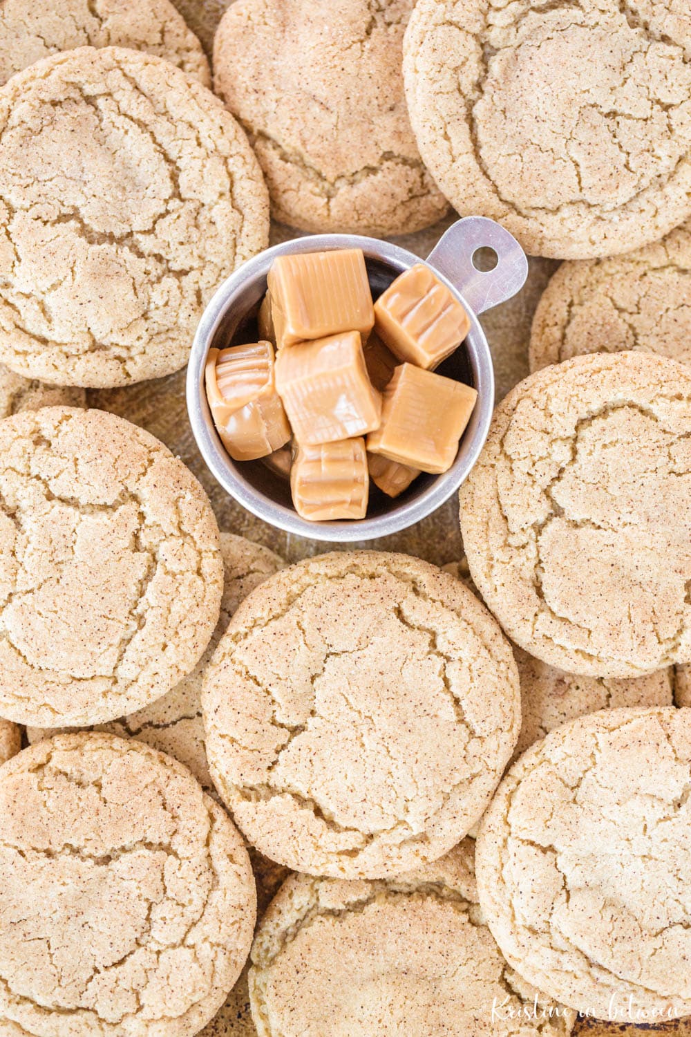 A pile of cookies with a cup of caramel candies in the center.