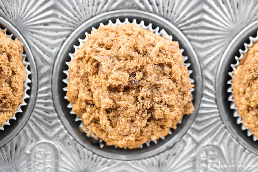 A muffin sitting in a muffin tin with brown sugar on top.