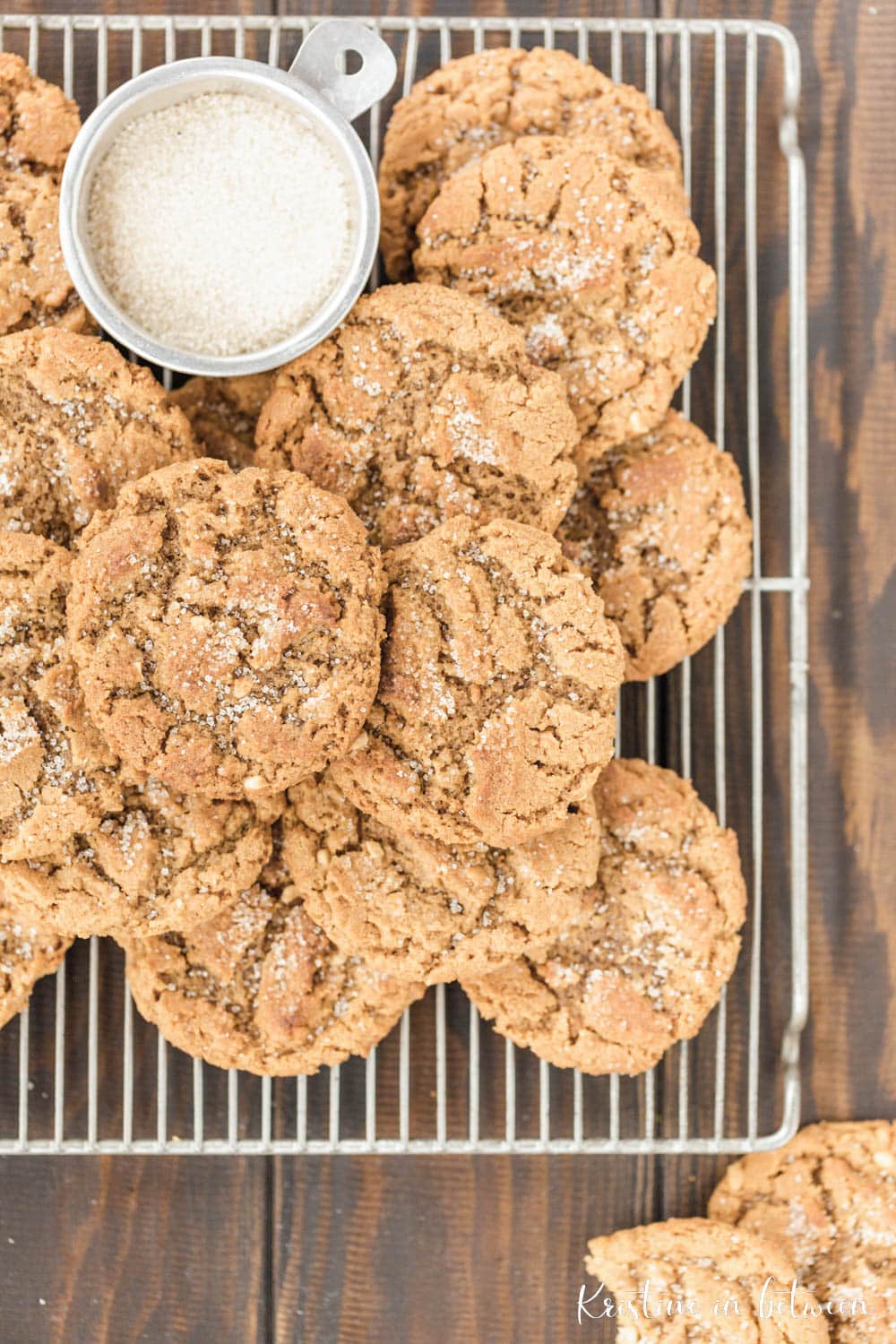 Cookies stacked up on a wire rack with a small bowl of sugar.