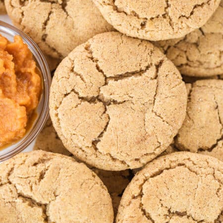 Cookies piled up with a small bowl of pumpkin puree nestled with them.