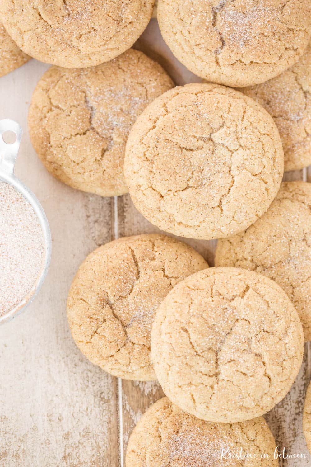 Cookies laying on a white antique wooden table with a small bowl of cinnamon and sugar.
