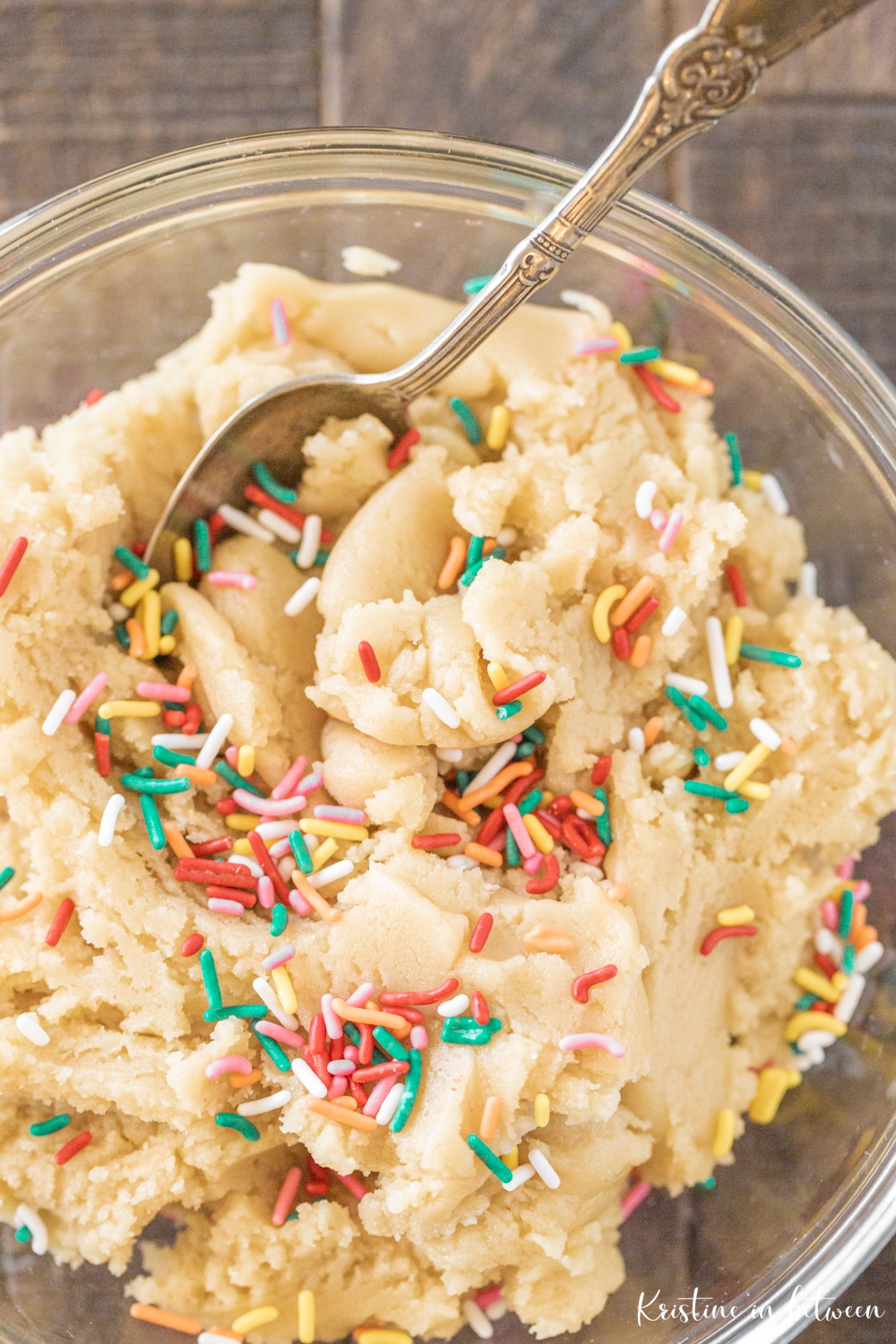 A bowl of cookie dough with sprinkles and a spoon.