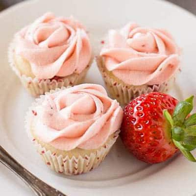 Cupcakes sitting on a plate with a strawberry.