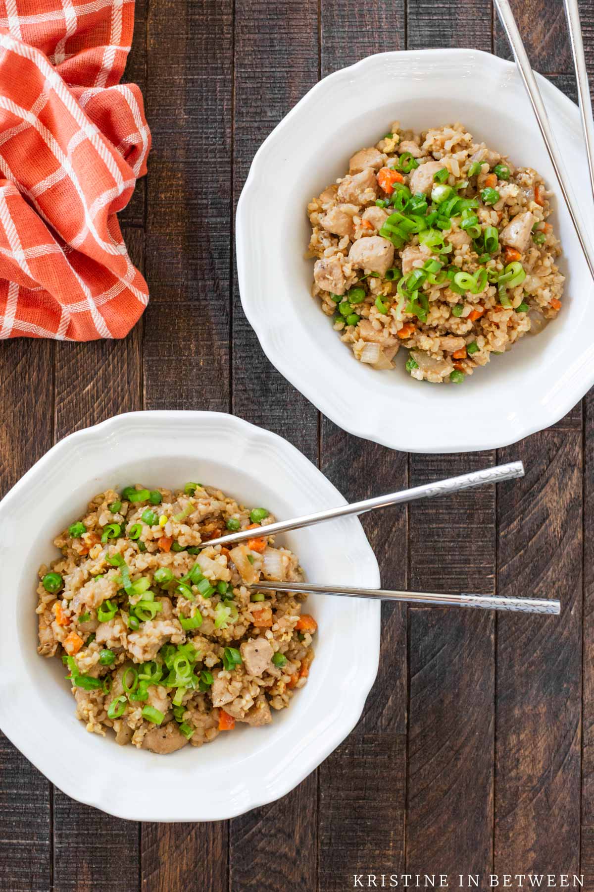 Two bowls of chicken fried rice with chopsticks.