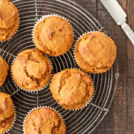 Pumpkin muffins sitting on a wire cooling rack with an antique knife next to them.