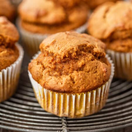 Pumpkin muffins sitting on a wire cooling rack with an antique knife next to them.
