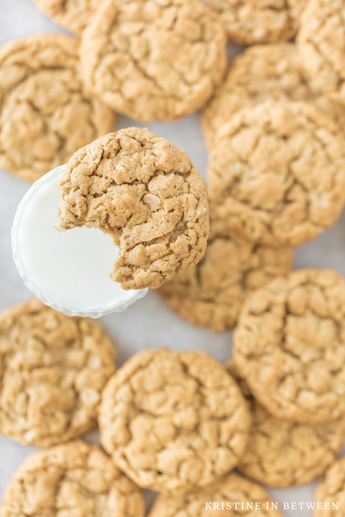 A cookie with a bite out of it balancing on a glass of milk.