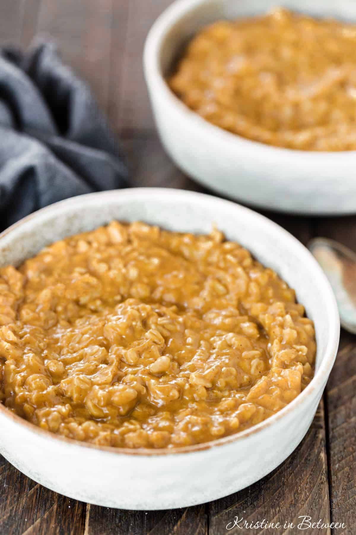 Two bowls of oatmeal with a dark blue napkin sitting next to them.