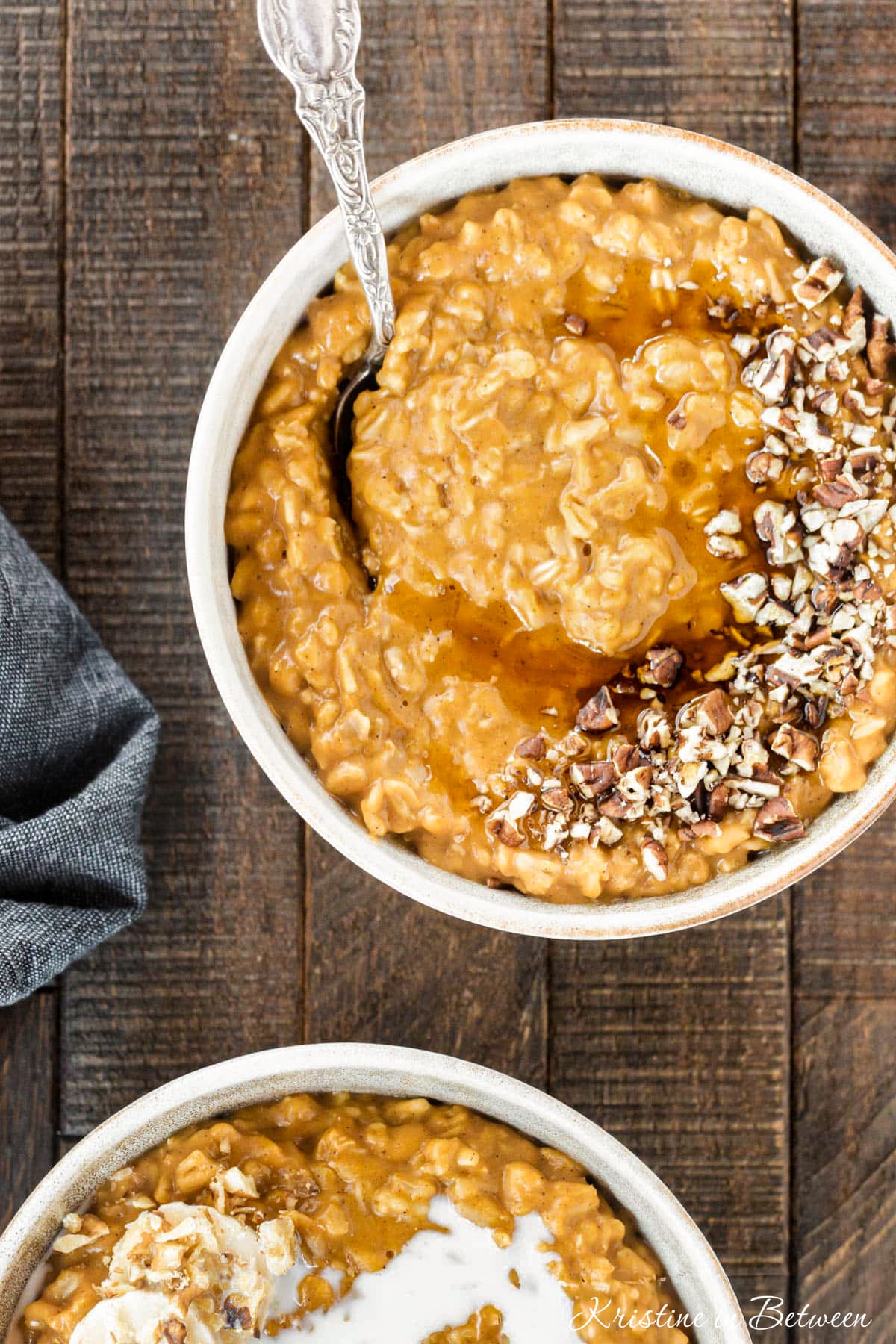 A bowl of pumpkin pie oatmeal topped with chopped pecans and a drizzle of maple syrup.