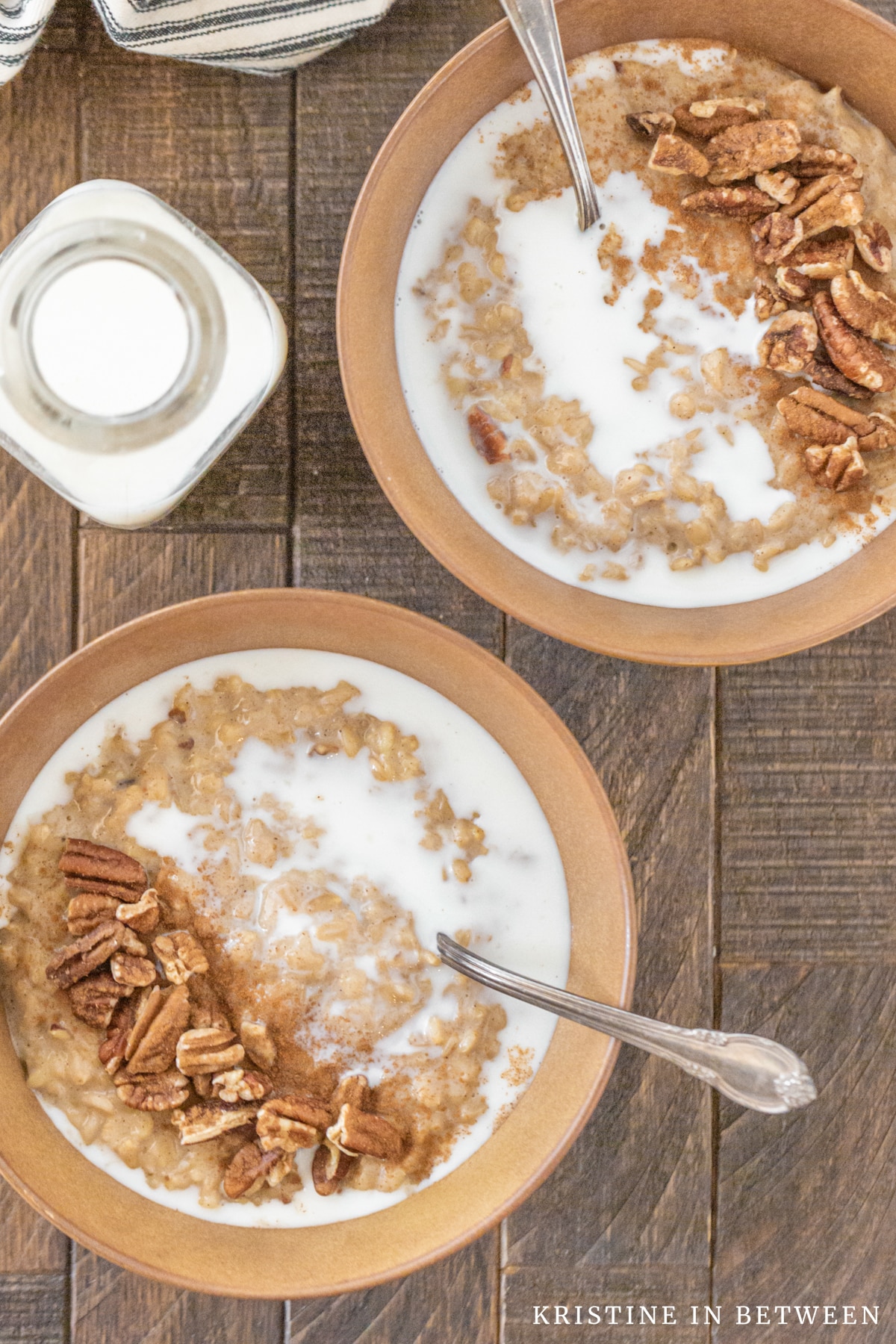 Two bowls of banana pecan oatmeal with milk and chopped pecans on top.