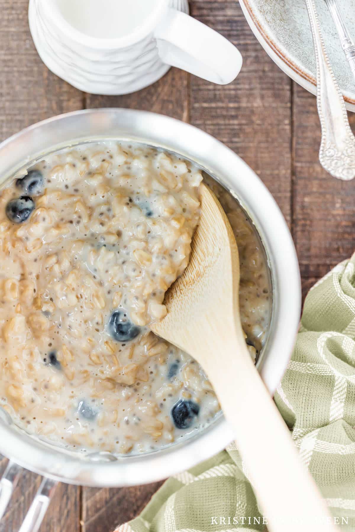 Blueberry muffin oatmeal in a pot with an orange napkin next to it.