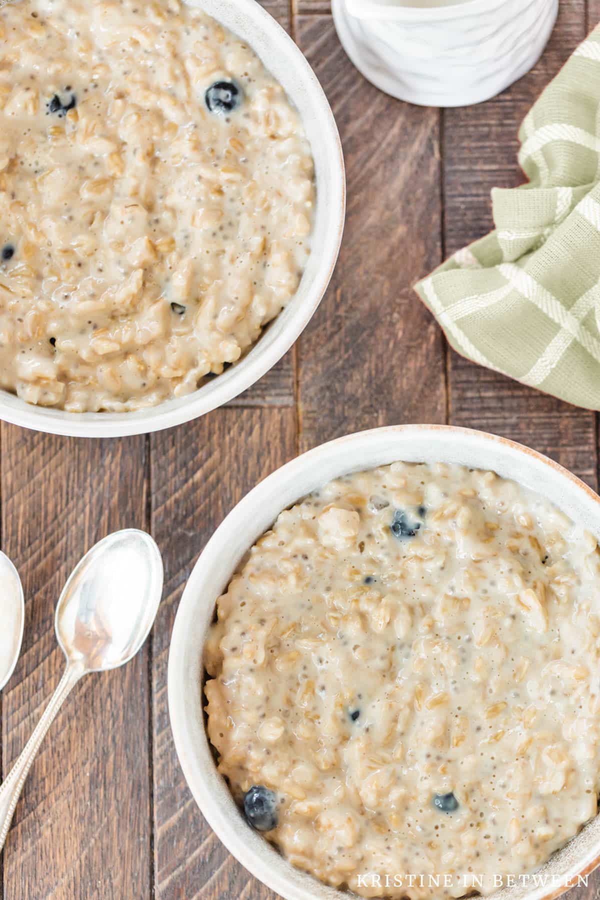 Two bowls of oatmeal without the topping and two spoons laying next to them.