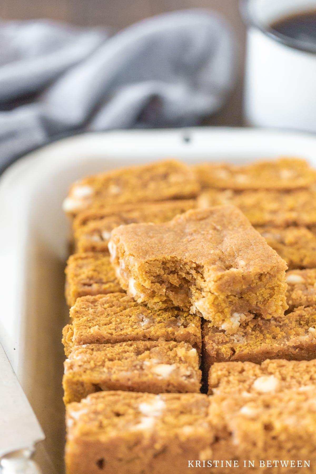 A blondie with a bite out of it laying on a pile of other blondies with a knife next to them.