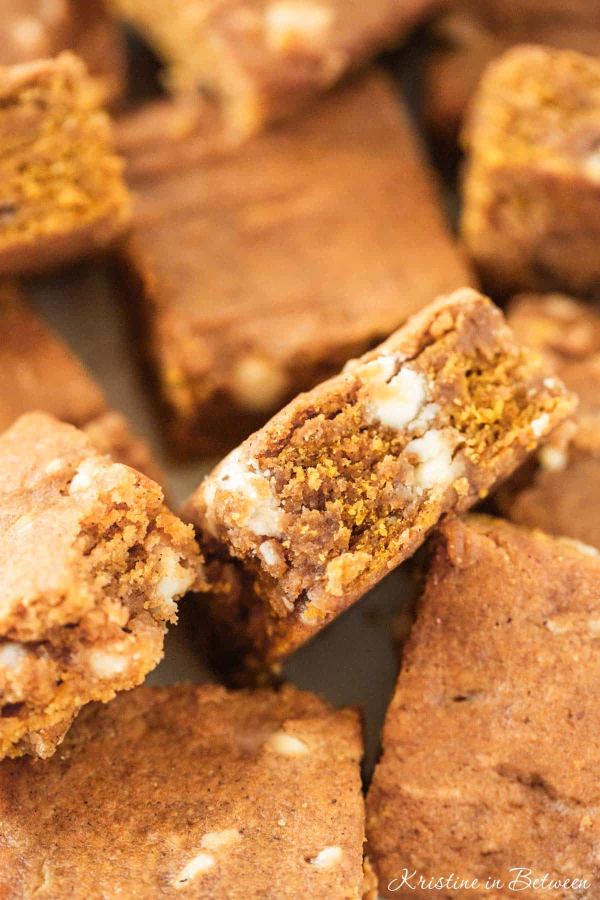 A closeup of pumpkin blondies showing the texture and white chocolate chips inside.
