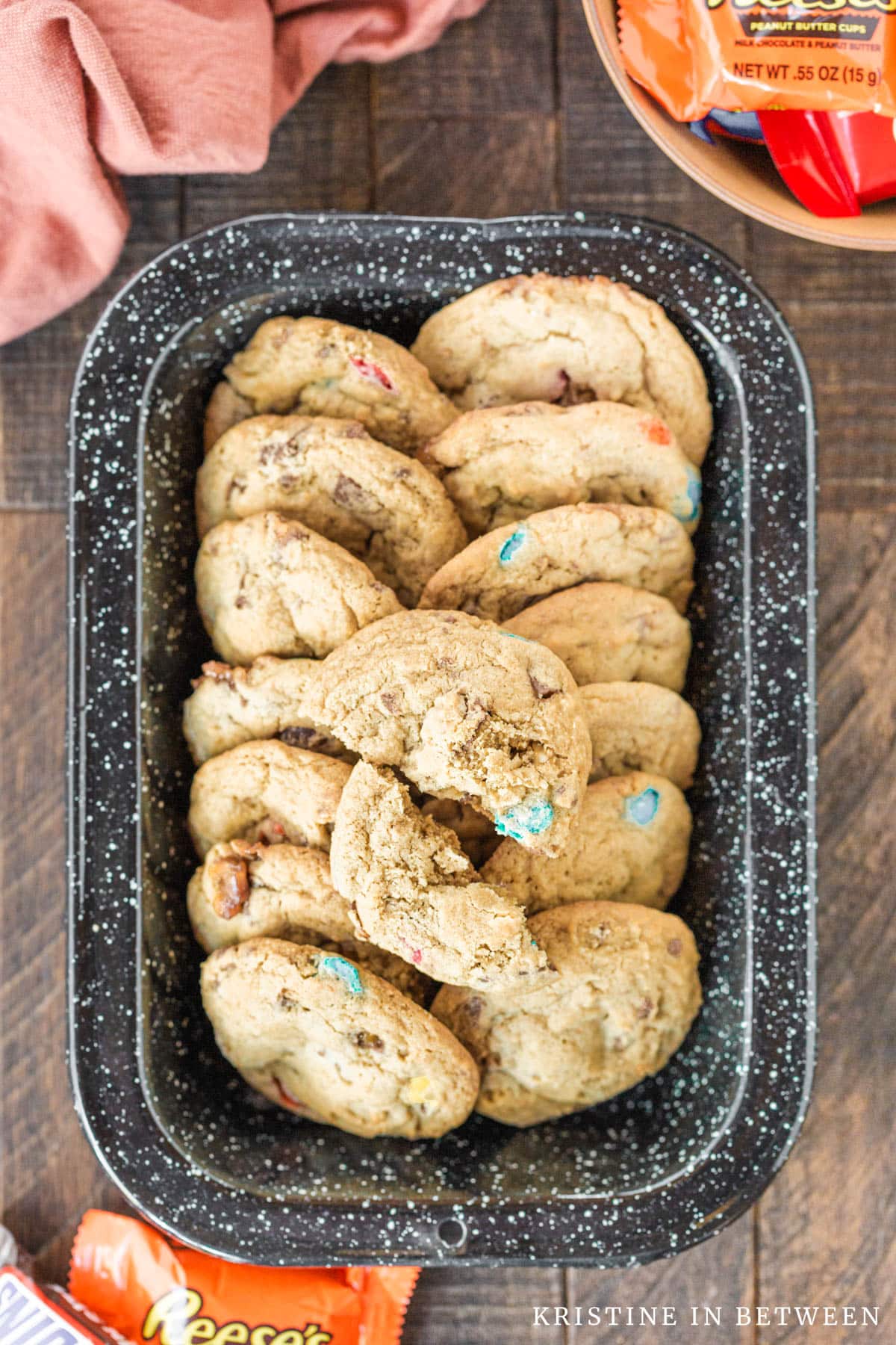 Cookies in a black speckled tin with candy in the background.
