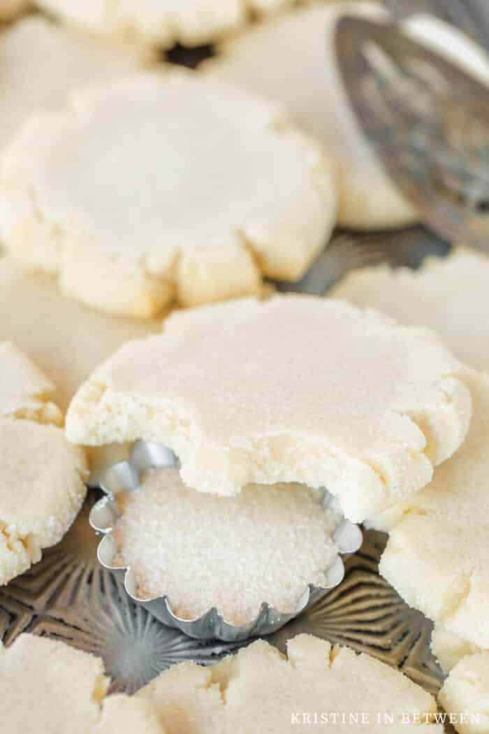 A sugar cookie with a bite out of it laying on top of other sugar cookies.