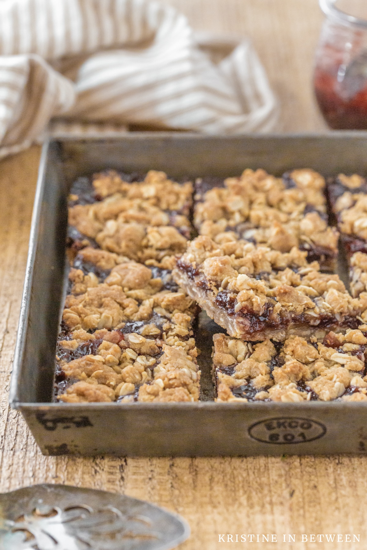 Raspberry jam bars in an old baking pan with one laying on top.