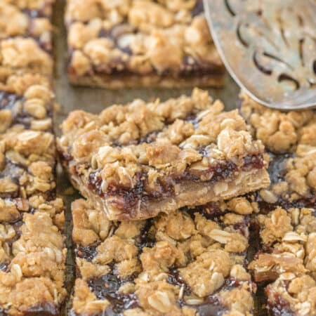 Raspberry jam crumble bars sitting in an antique baking pan with an old spatula.
