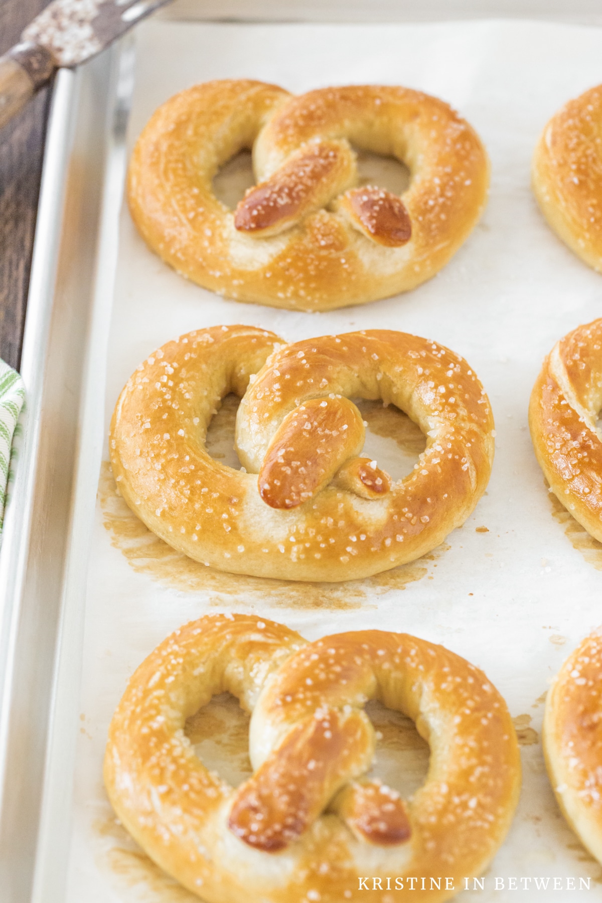 A tray of soft, salted pretzels with a green striped napkin sitting next to them.