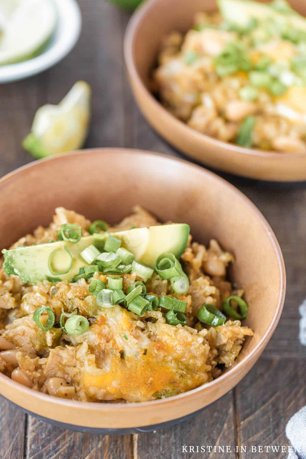 White chicken chili in a bowl topped with avocado and green onion.