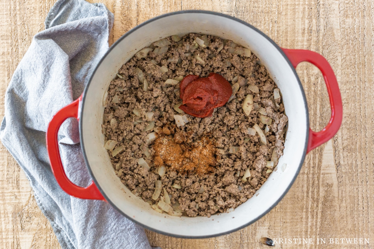 Cooked ground beef and onions with tomato paste and seasonings on top.