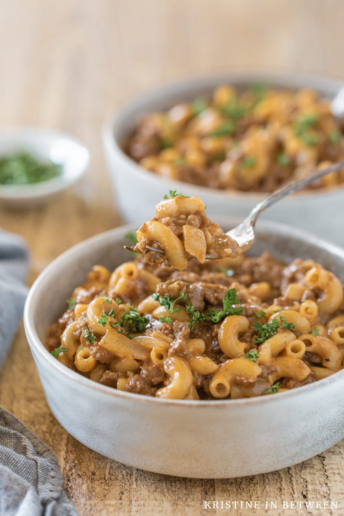 Chili mac in a bowl with a fork with a bite on it.