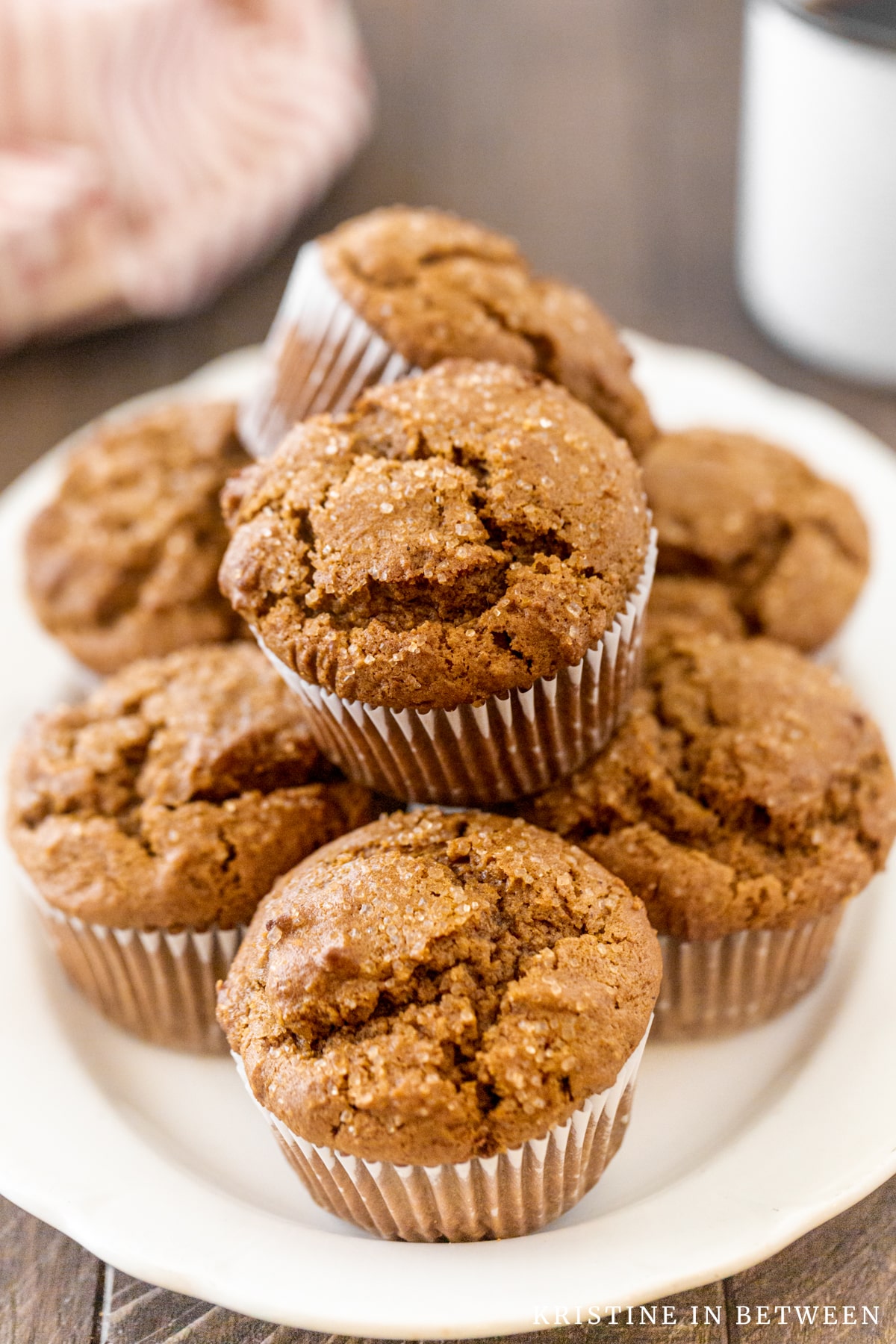 A muffin plate full of gingerbread muffins with a cup of coffee in the background.