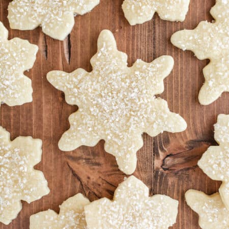 Cut out sugar cookies laying on a wooden table.
