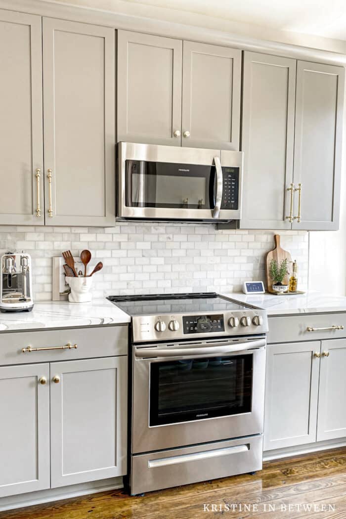 A gray and white kitchen with stainless steel appliances.