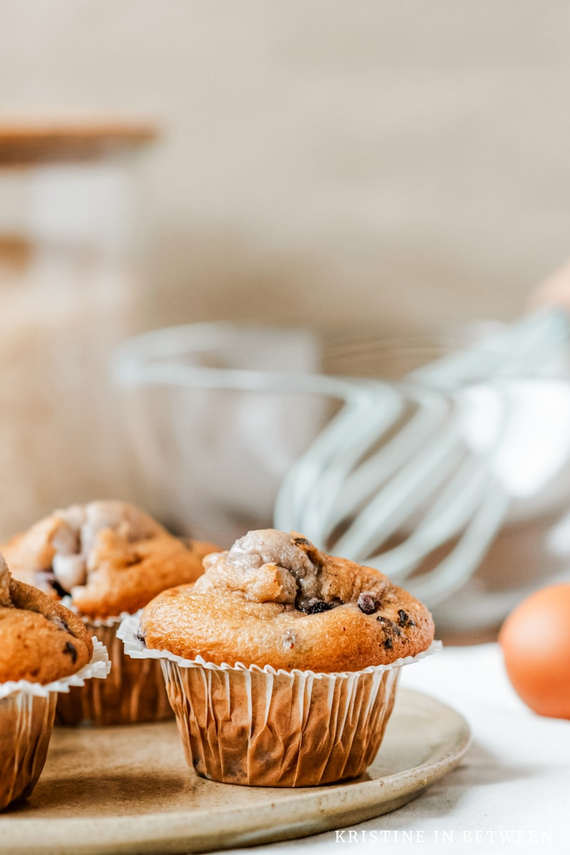 Muffins sitting on a plate with a whisk and a mixing bowl in the background.