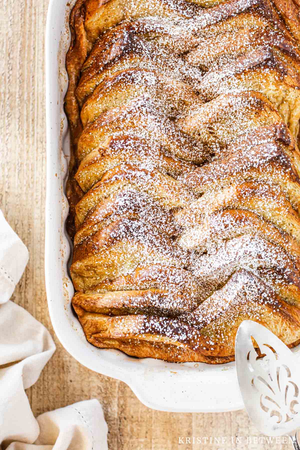 Baked French toast in a casserole dish with powdered sugar on top.